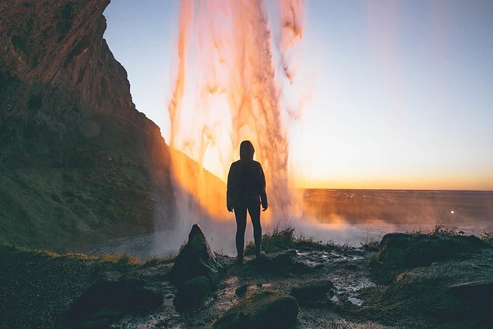 A person standing behind the Seljalandsfoss waterfall in Iceland