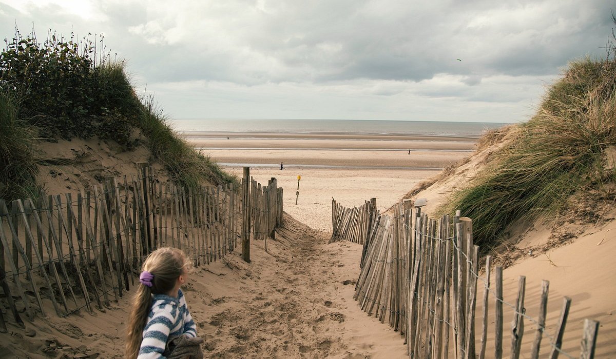 A child going to the beach on a cold, windy day at Formby, Liverpool in England