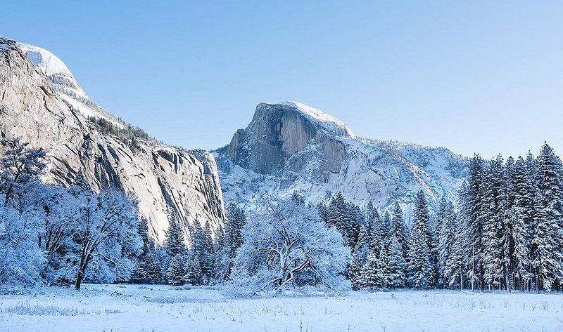 A snow-covered meadow looks out on a dusted Half Dome 