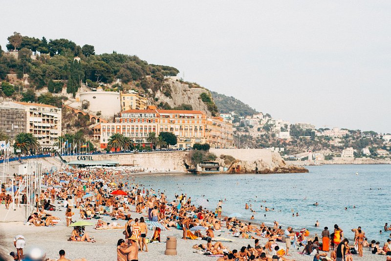 Strandbesökare som kopplar av på en strand i Nice, Frankrike