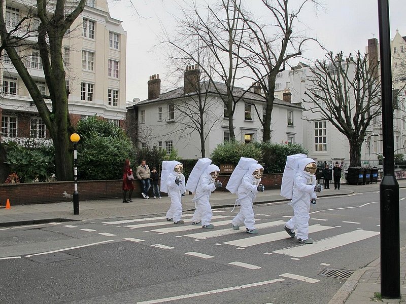 Four people in space suits walking down Abbey Road in London