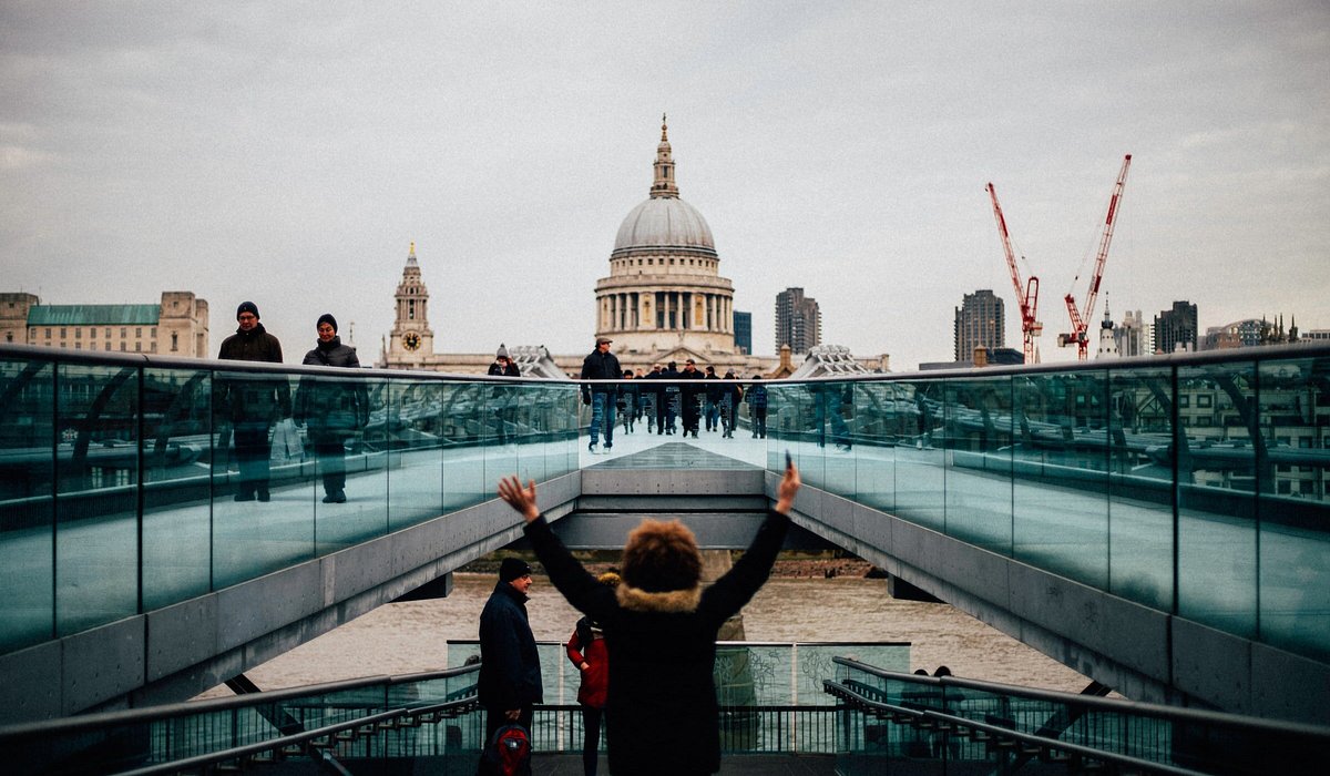 A person standing on the Millennium Bridge in London with the St Pauls Cathedral in the background