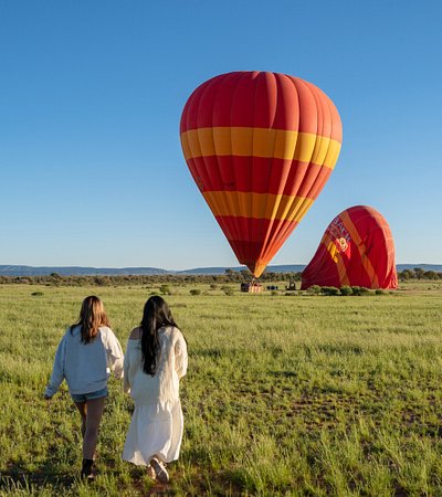 Two women looking at two hot air balloons in Alice Springs 