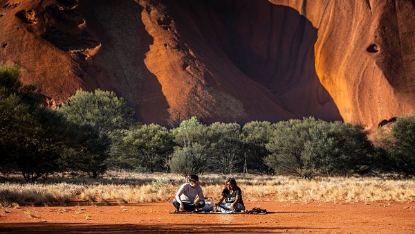 A visitor learning dot painting with a local Aboriginal artist from Maruku Arts