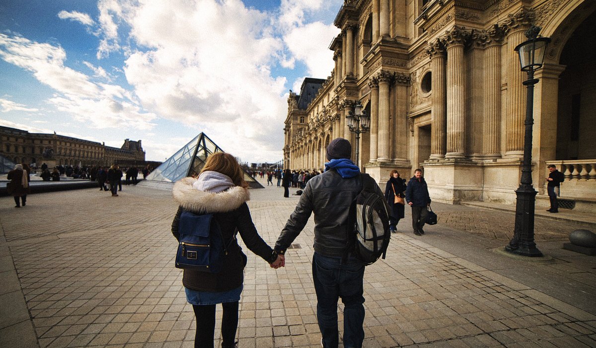 파리 루브르 박물관을 배경으로 손을 잡고 있는 커플