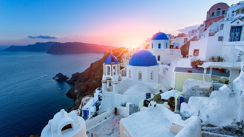 Blue domed churches at sunset in Oia, Santorini, Greece