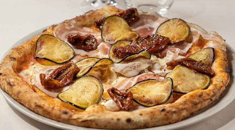 Pizza Montanara: pomodoro, mozzarella, pancetta arrotolata, melanzane fritte, pomodori secchi 