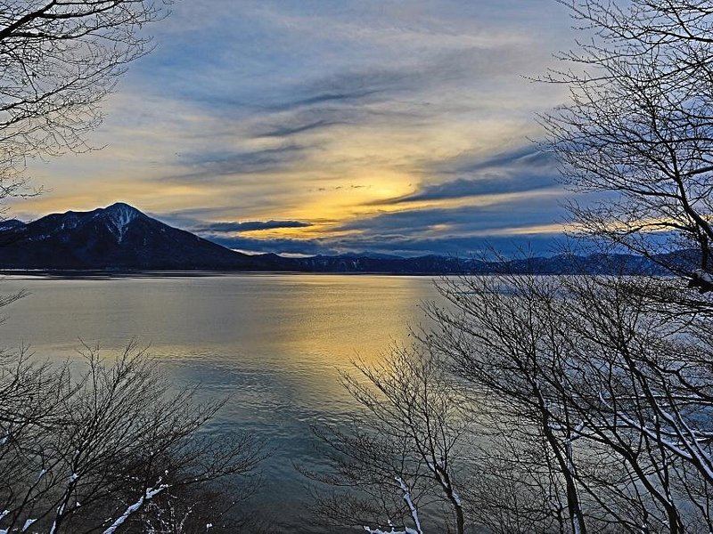 View of a blue lake as the sun sets behind