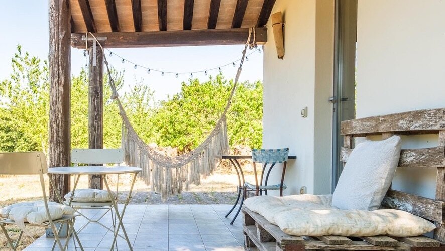 Portico esterno attrezzato con sedie, tavoli divanetto, e amaca