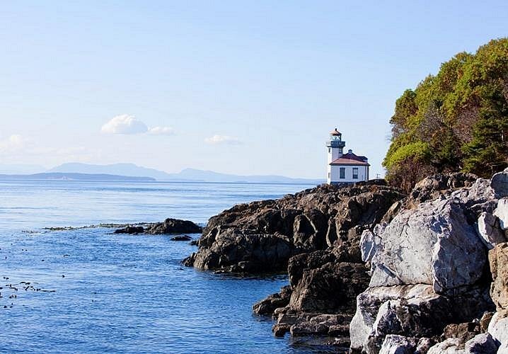 A light house at the edge of San Juan Island among a bright blue sea