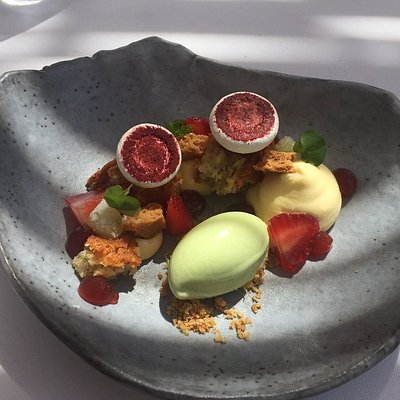 Gray dessert plate with strawberries, cream, and various garnishes