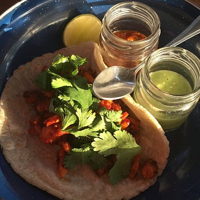 Taco alongside glass jars of red and green salsa