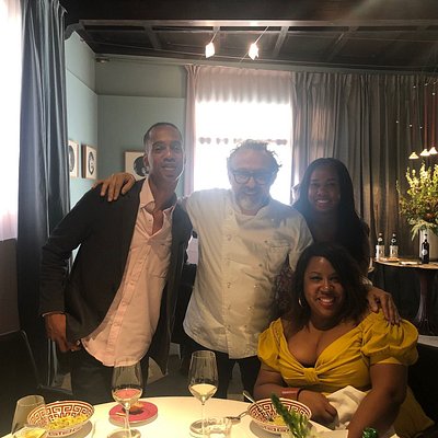 Three people and chef smiling at table