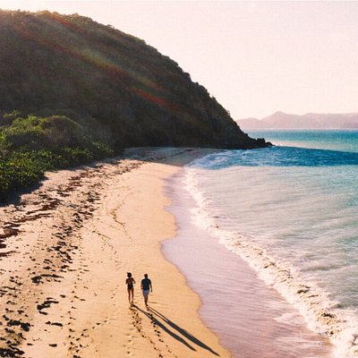 A couple walks down the sunny Grande Anse beach in Guadeloupe beach in the Caribbean