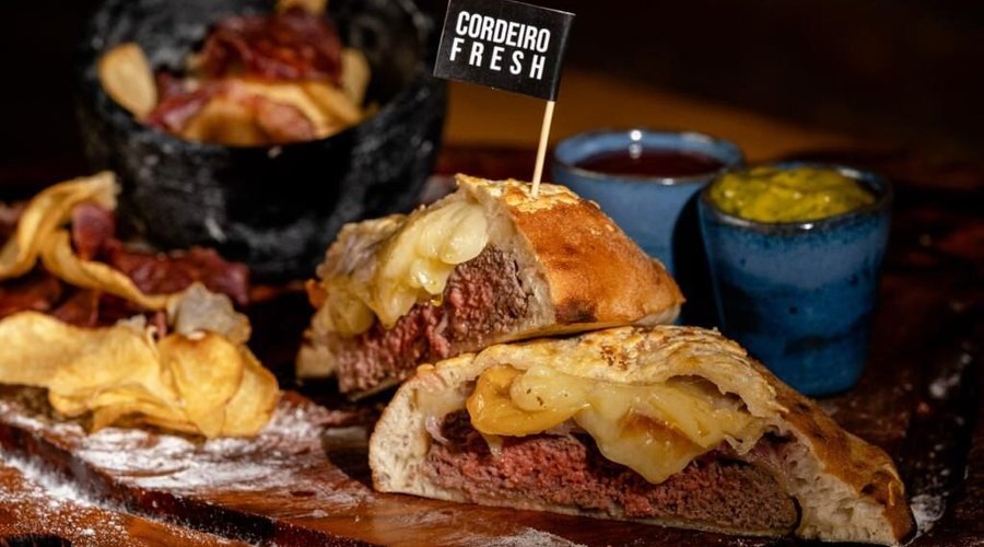 Exclusivo hambúrguer de Cordeiro (160g), queijo Fior di Latte e bacon. Acompanhado de batatas rústicas, rúcula e tomate confitado, maionese da casa e ketchup da casa. 