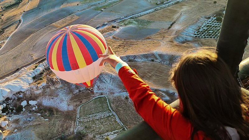 Girl pointing to hot-air balloon over Cappadocia, Turkey 