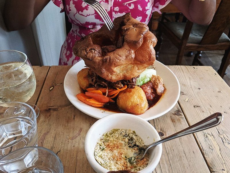 A woman eating a massive yorkshire pudding at The Pig & Butcher in London