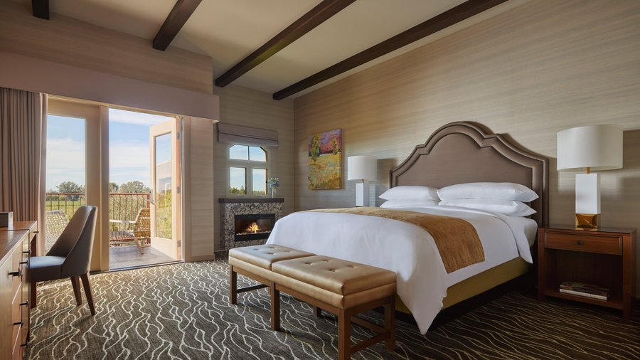 Vineyard View Fireplace King Room at Vintners Resort features a California king feather bed with plush down bedding, a fireplace, and a door opens to a furnished patio or balcony.