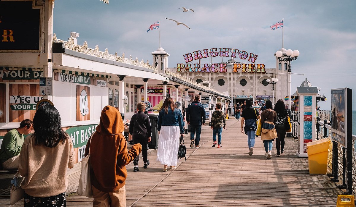 People walking on a boardwalk towards Brighton Palace Pier