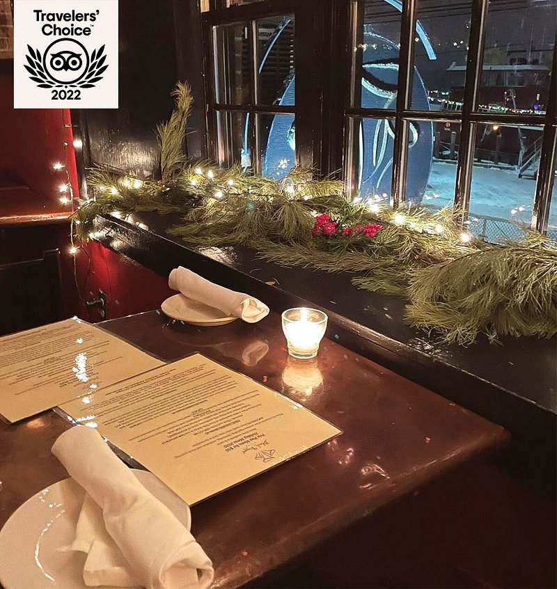 Restaurant table with candles next to window lined with garland