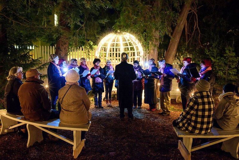 Carolers singing next to lit-up gazebo at night
