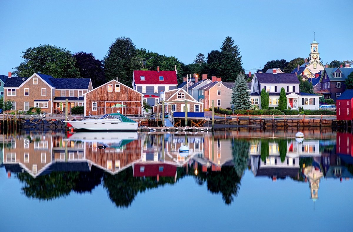 Body of water lined with charming houses in various colors and ample green trees