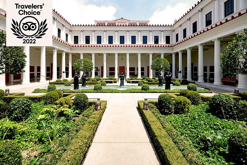 Courtyard of two-story villa with columns, featuring a fountain and manicured garden