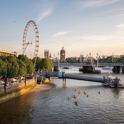 A pink sunrise view over the River Thames with the London Eye in the distance