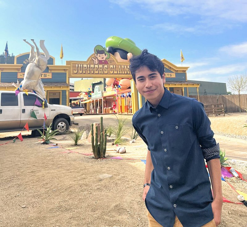 Benenfeld wearing blue button-up shirt standing outside of Jupiter's Claim attraction
