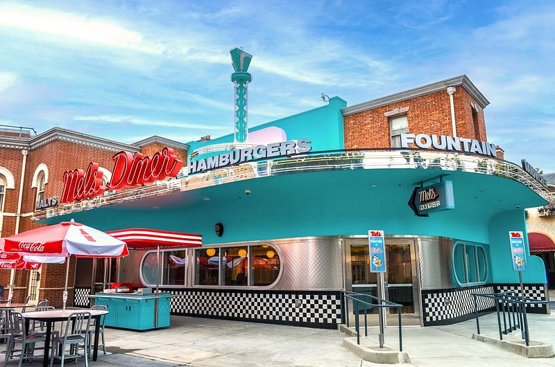 Exterior of retro 50s-style diner with turquoise, metal, and black-and-white checkered exterior and large red name sign