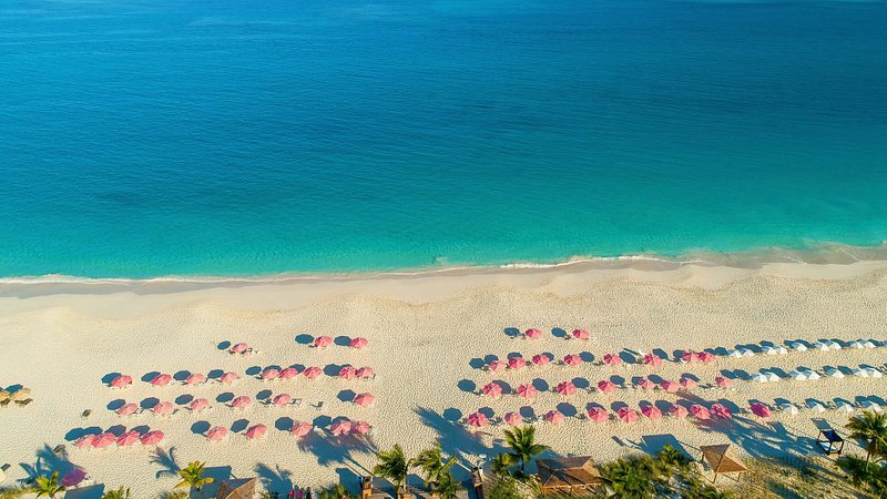 Aerial view of beach with pink umbrellas, in Grace Bay, Turks and Caicos 