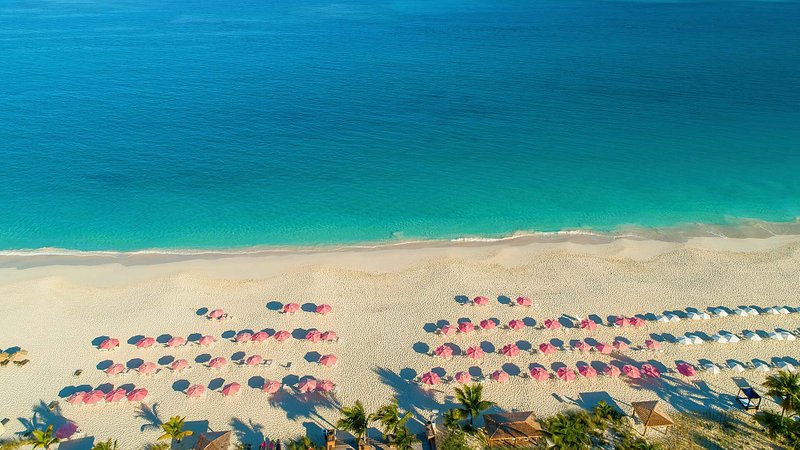 Aerial view of beach with pink umbrellas, in Grace Bay, Turks and Caicos