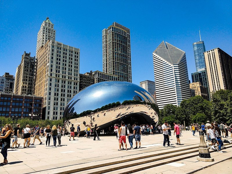 The Cloud Gate sculpture, also known as "The Bean," with visitors walking around it and the skyline in the background