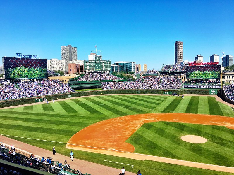 A sunny, blue-sky day at Wrigley Field, with crowds filling the seats surrounding the green baseball field