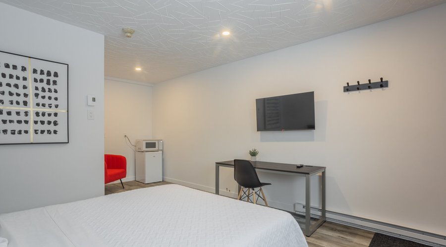 Chambre un lit queen avec table, TV intelligente, frigo et micro ondes.