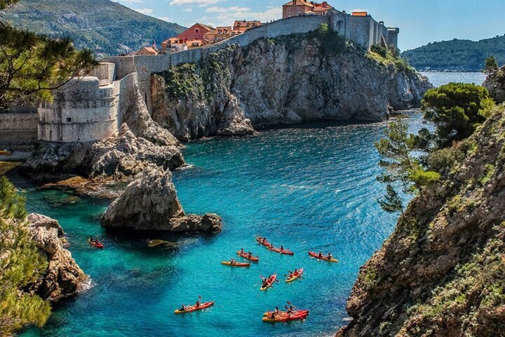 Kayakers paddling in the pristine blue waters around Dubrovnik's ancient city walls, enjoying an active way to explore the coastline.