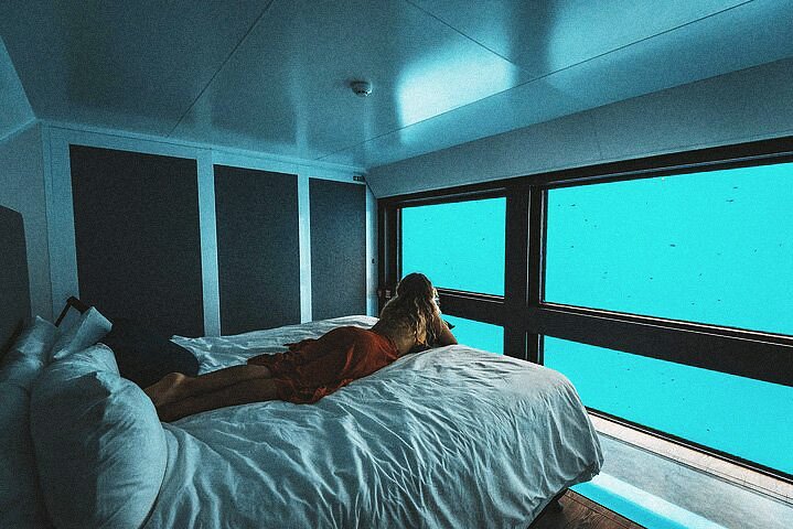 Γυναίκα που απολαμβάνει τη θέα στη θάλασσα σε ένα υποβρύχιο δωμάτιο ξενοδοχείου στην Αυστραλία.