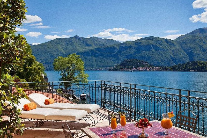 イタリアのコモ湖を望む、サンベッドとテーブルが置かれた屋外テラス。