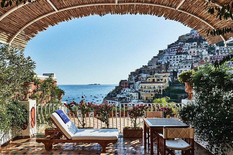 Terrasse extérieure d'un hôtel avec vue sur la côte amalfitaine et les falaises de Positano, en Italie.