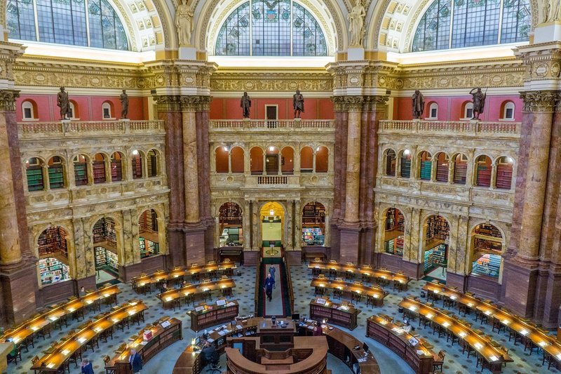 Interior rotunda with desks, large marble columns, and stained glass windows