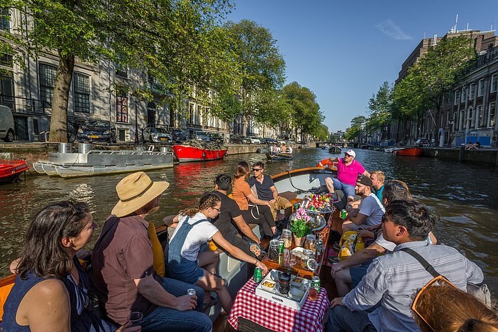 Group of people on canal cruise, with buckets of drinks and food displayed