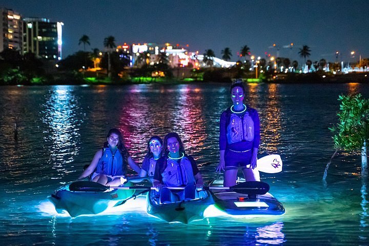 Four female travelers kayaking at night on the Condado Lagoon in San Juan, Puerto Rico