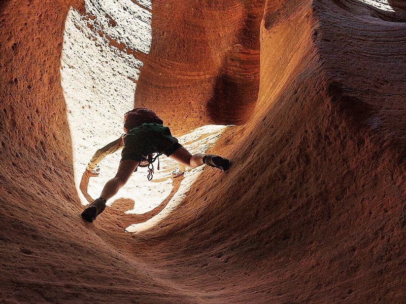 A traveler slowly climbing up a canyon in Zion National Park, Utah