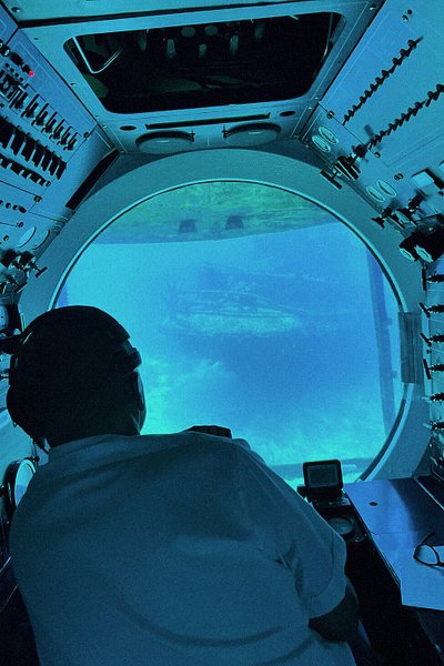 Rear shot of a captain looking at a shipwreck through a submarine window