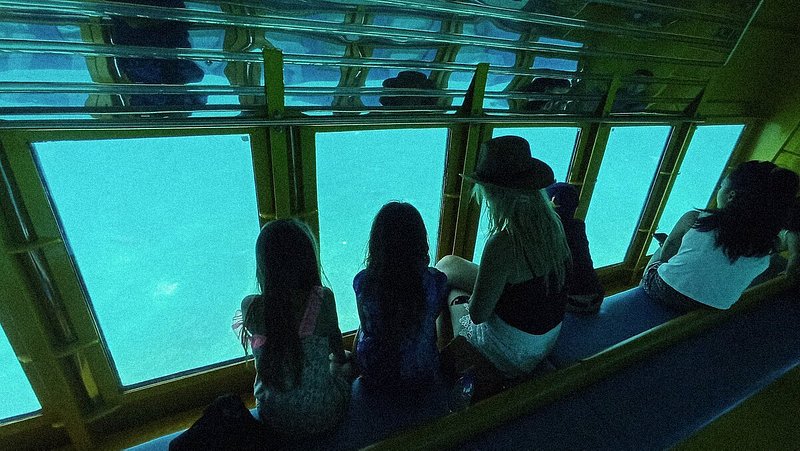 A female traveler and three kids in a submarine looking at the seabed of Mirabello Bay in Agios Nikolaos, Crete