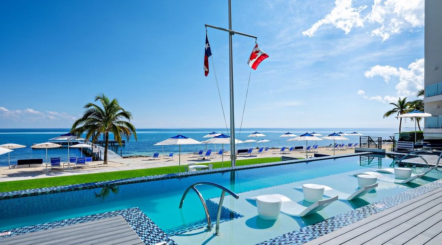 Heated infinity pool overlooking our private beachfront with sun beds and shade umbrellas. 