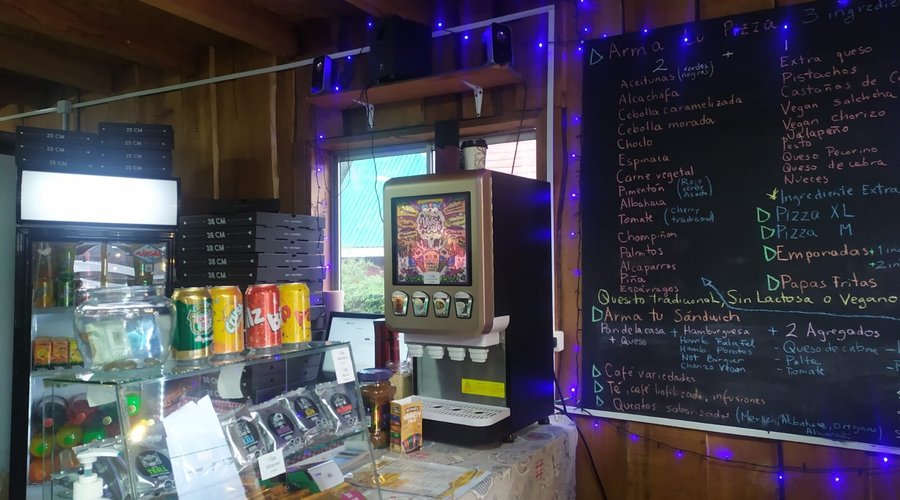 Parte del interuir de nuestro local, puedes apreciar la pizarra con todos los ingredientes que tenemos disponibles, ya sea para pizzas, empanadas, sándwichs, empanadas, contamos con máquina de café, al igual que con cafés libre de lactosa y sin gluten, puedes ver además una gran variedad de alfajores Valdivianos Bundor y Dulce Lluvia.