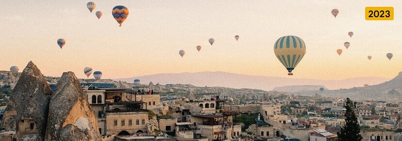 Multiple hot air balloons floating over a cityscape and fairy chimneys in Cappadocia, Turkey