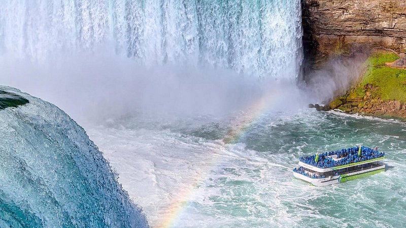 Maid of the Mist boat under a rainbow in front of Niagara Falls, New York