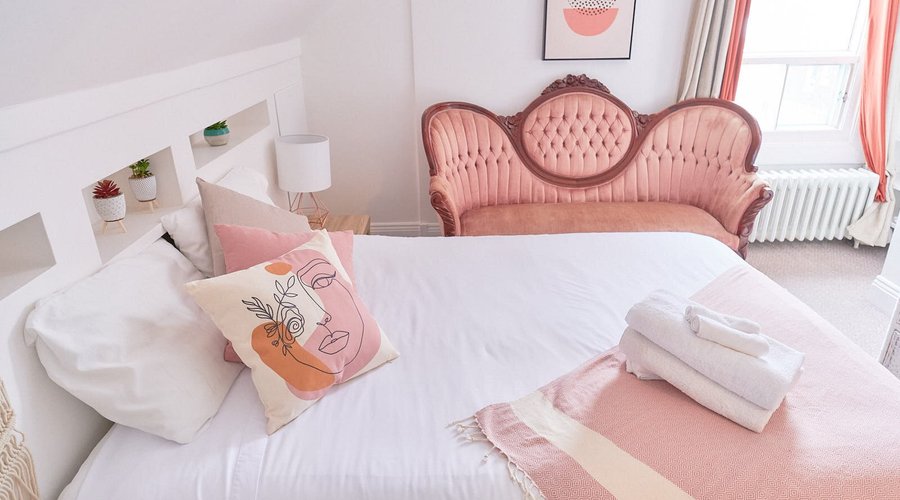 Belle grande chambre avec salle de bain privée, grand lit queen avec un grand divan de style rustique rose.